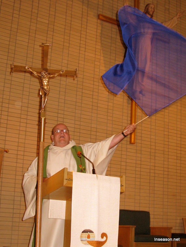 Fr. Tom waving a banner at the podium at the Espousal Center in Waltham, MA